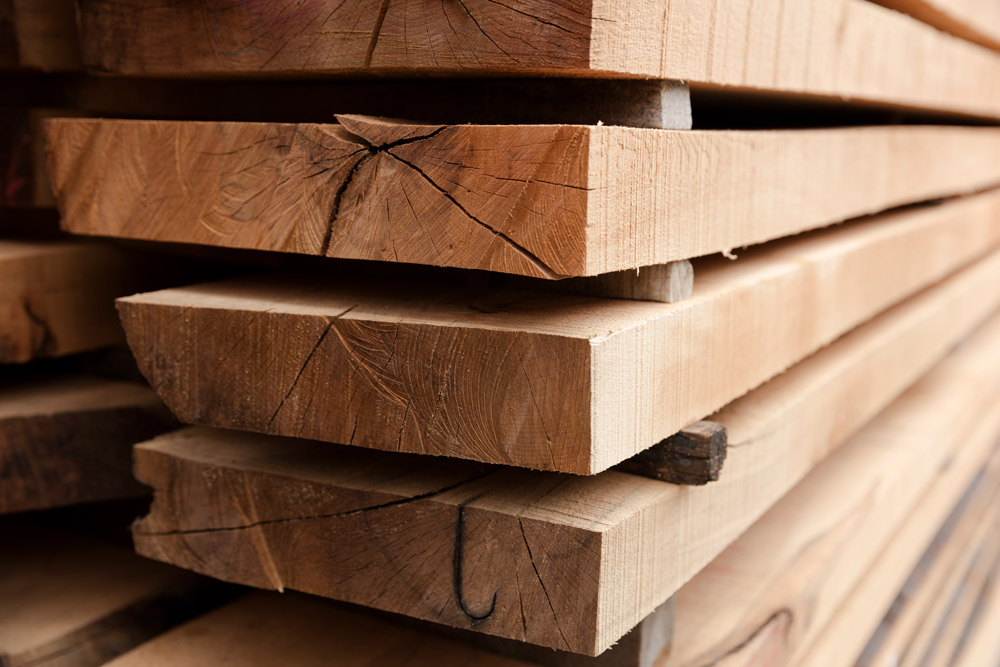 Close-up of stacked rough-sawn timber beams used in custom post-and-beam construction. The natural wood grain and texture highlight Sugarcreek Builder’s commitment to quality materials and craftsmanship in timber frame homes and barns.